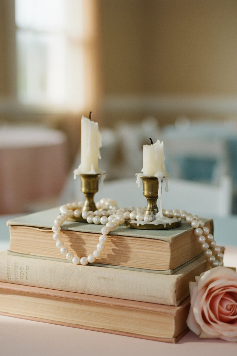 DIY girl baby shower decorations — stack vintage books with candles and pearls for a charming centerpiece